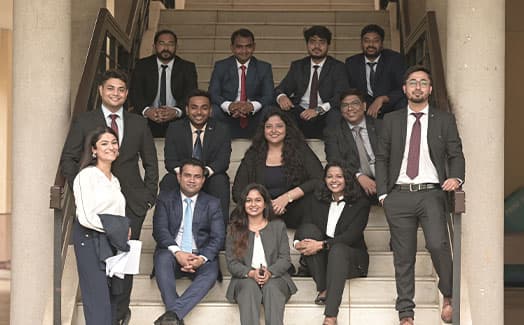 A student cohort seated on the steps of an XLRI campus building